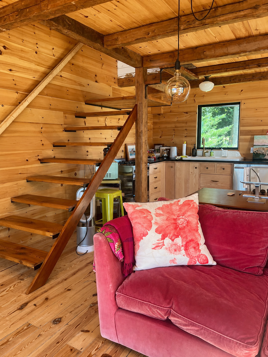 Open-tread wooden staircase beside a compact kitchen in natural wood
